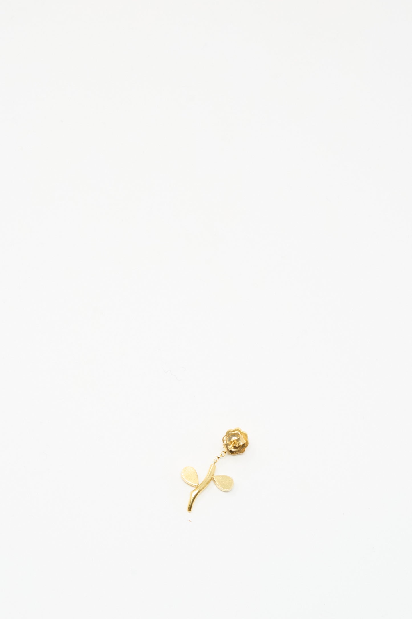 The Grainne Morton Flower Stem Drop Earring is a small gold rose-shaped piece with two leaves, displayed on a plain white background.