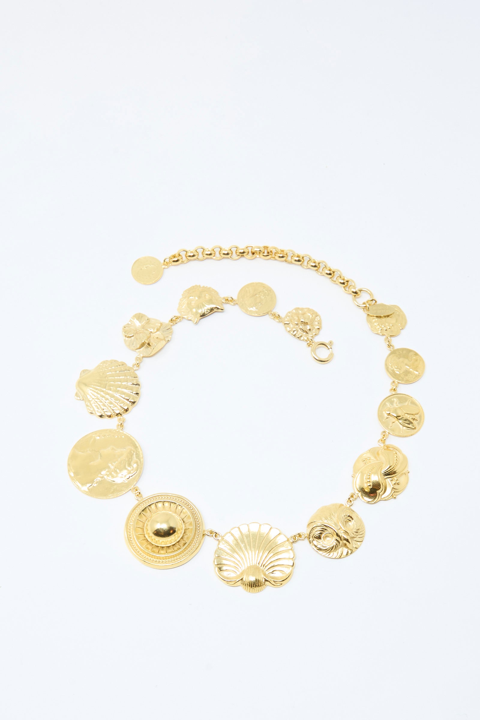 The Gold Button Necklace by Grainne Morton is a gold-plated silver chunky belcher chain with round and shell-shaped pendants, shown arranged in a circular layout on a white background.