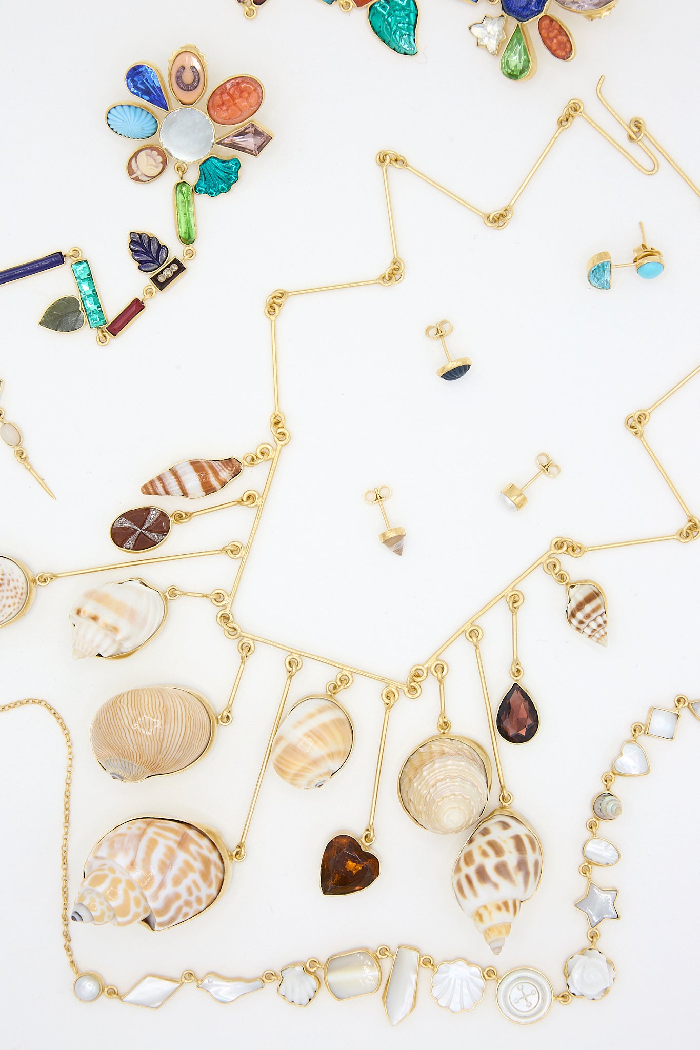 A collection of necklaces, earrings, and shells featuring the Grainne Morton Five Charm with Victorian Drop Earrings in 18k gold-plated silver.
