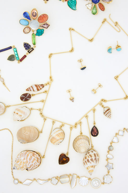 A collection of necklaces, earrings, and shells, including Grainne Morton's 18k gold-plated silver stud earrings in blue pearl.