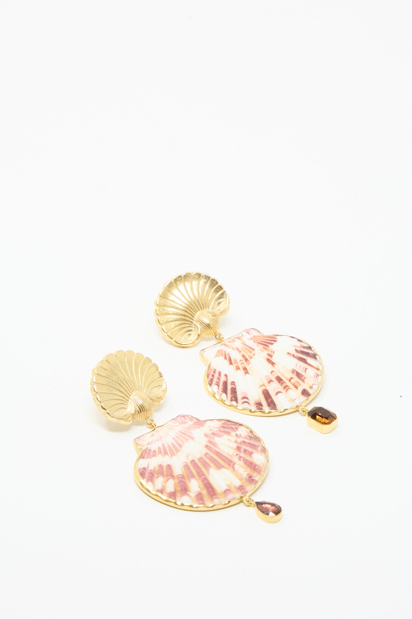 Scallop Earrings by Grainne Morton feature gold shell shapes with purple and white designs, accented by a small amber gem drop, against a white backdrop. 