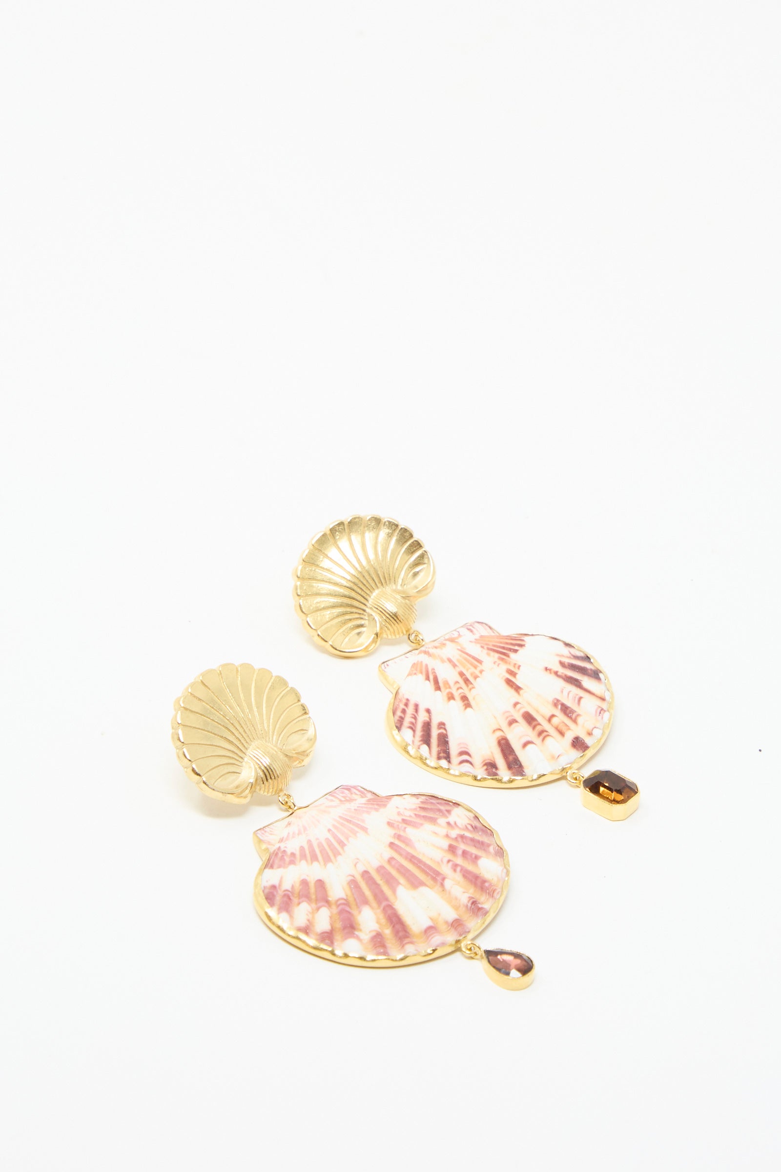 Scallop Earrings by Grainne Morton feature gold shell shapes with purple and white designs, accented by a small amber gem drop, against a white backdrop. 