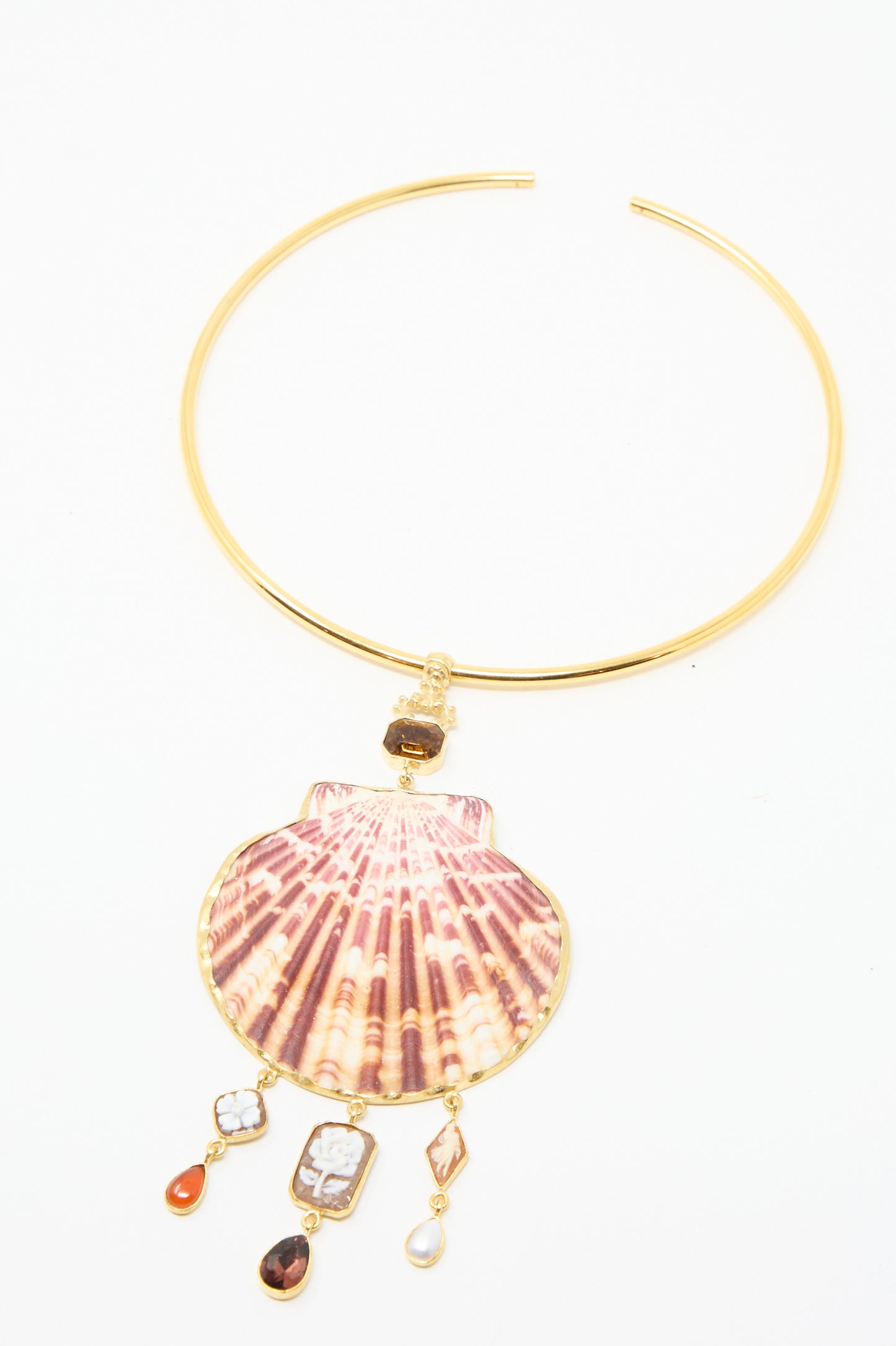 The Scallop Necklace by Grainne Morton is an 18k gold-plated silver torque piece with a large red striped shell pendant, accented by smaller colorful stones and beads hanging below.