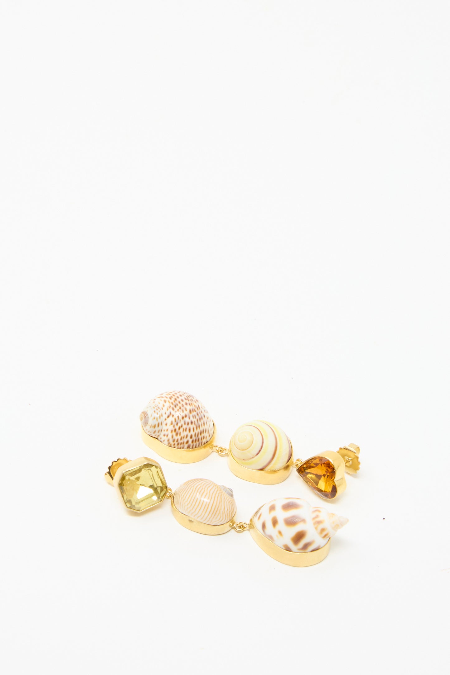 Grainne Morton's Shell Charm Drop Earrings lay against a white background and feature a combination of shells and amber gemstones. 