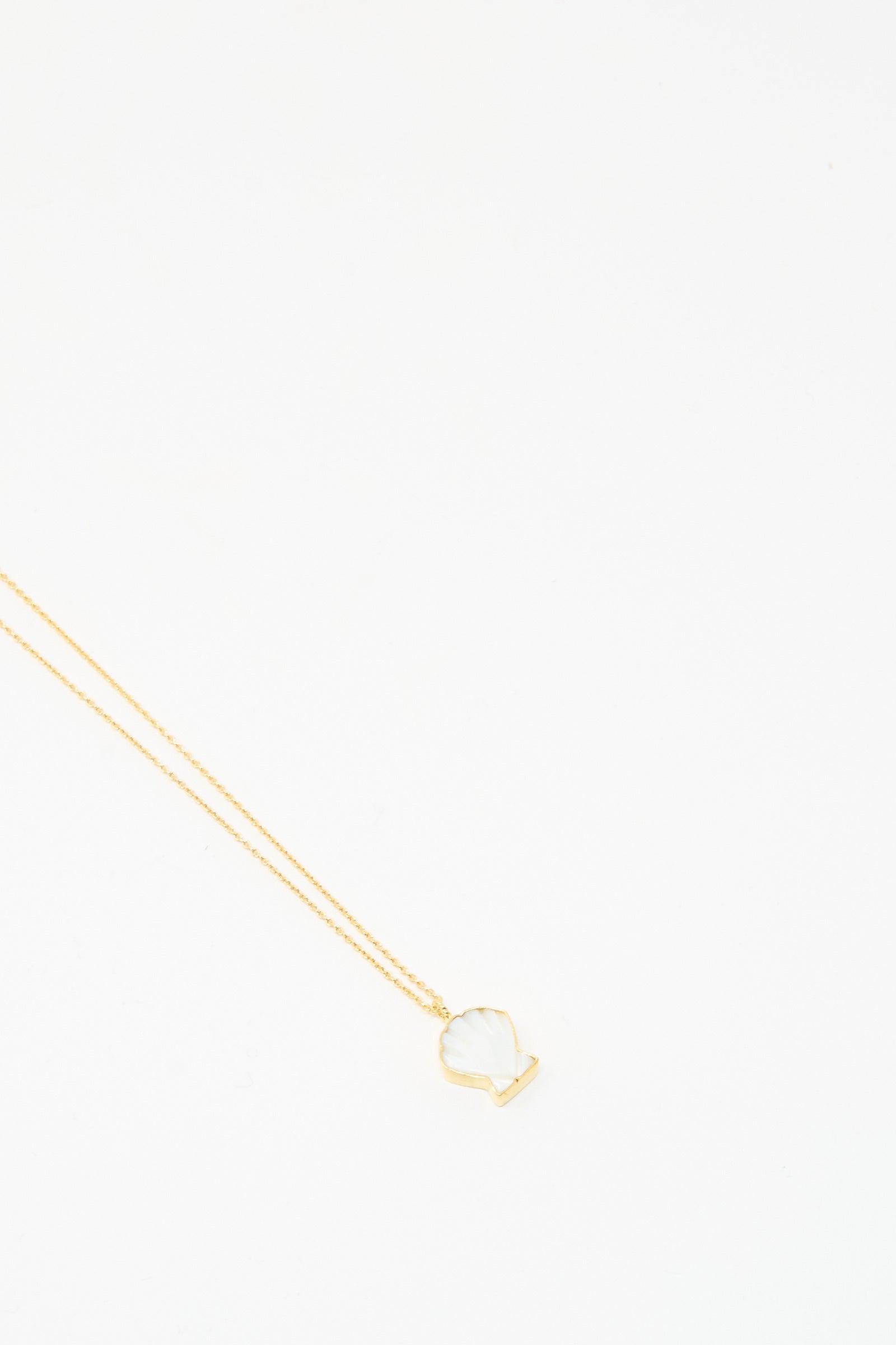 The Grainne Morton Shell Charm Necklace features a gold shell and mother of pearl pendant on a gold-plated chain, shown against a plain white background.