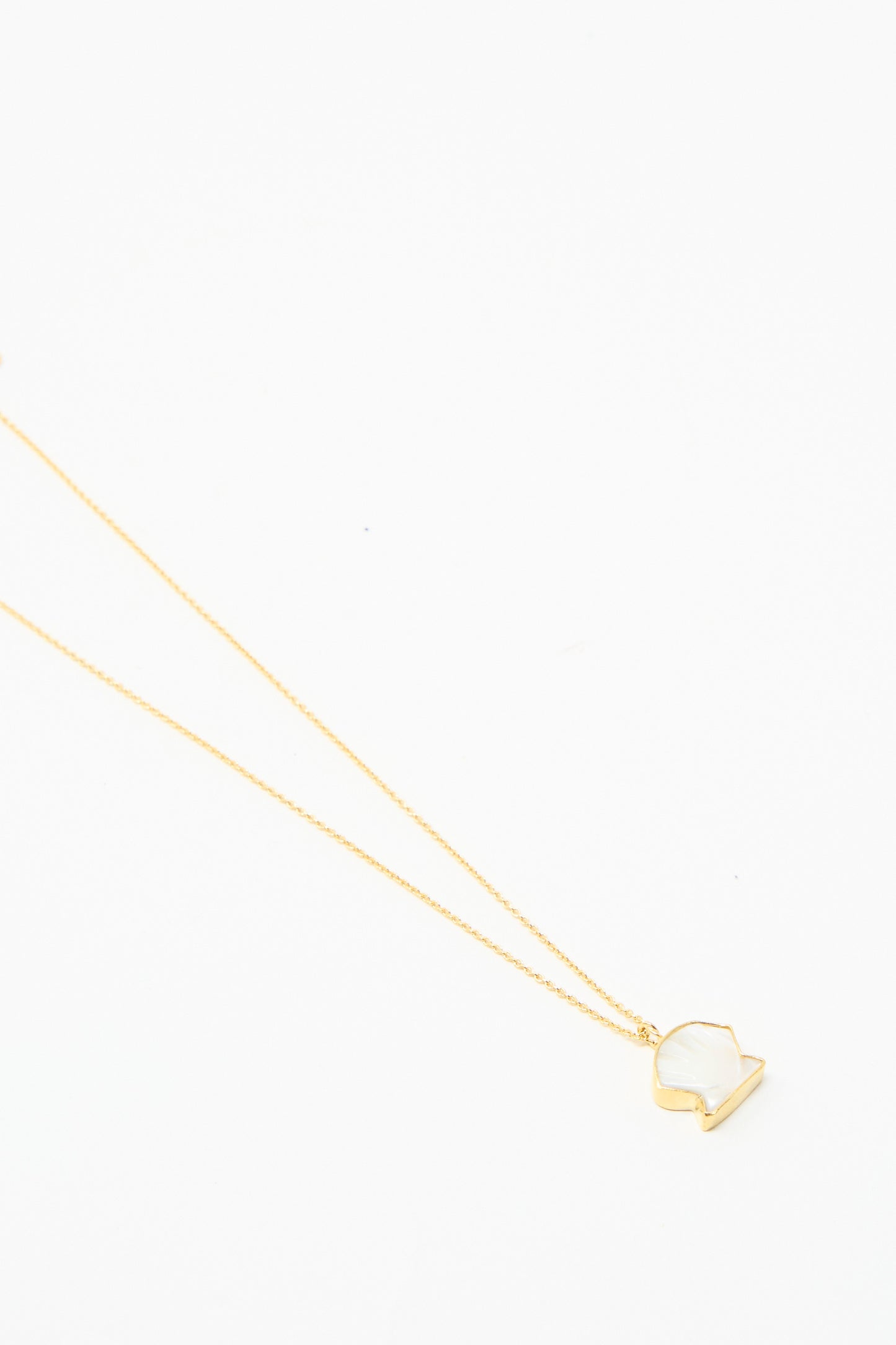 The Grainne Morton Shell Charm Necklace is gold-plated silver with a pendant in the shape of a shell on a white background.