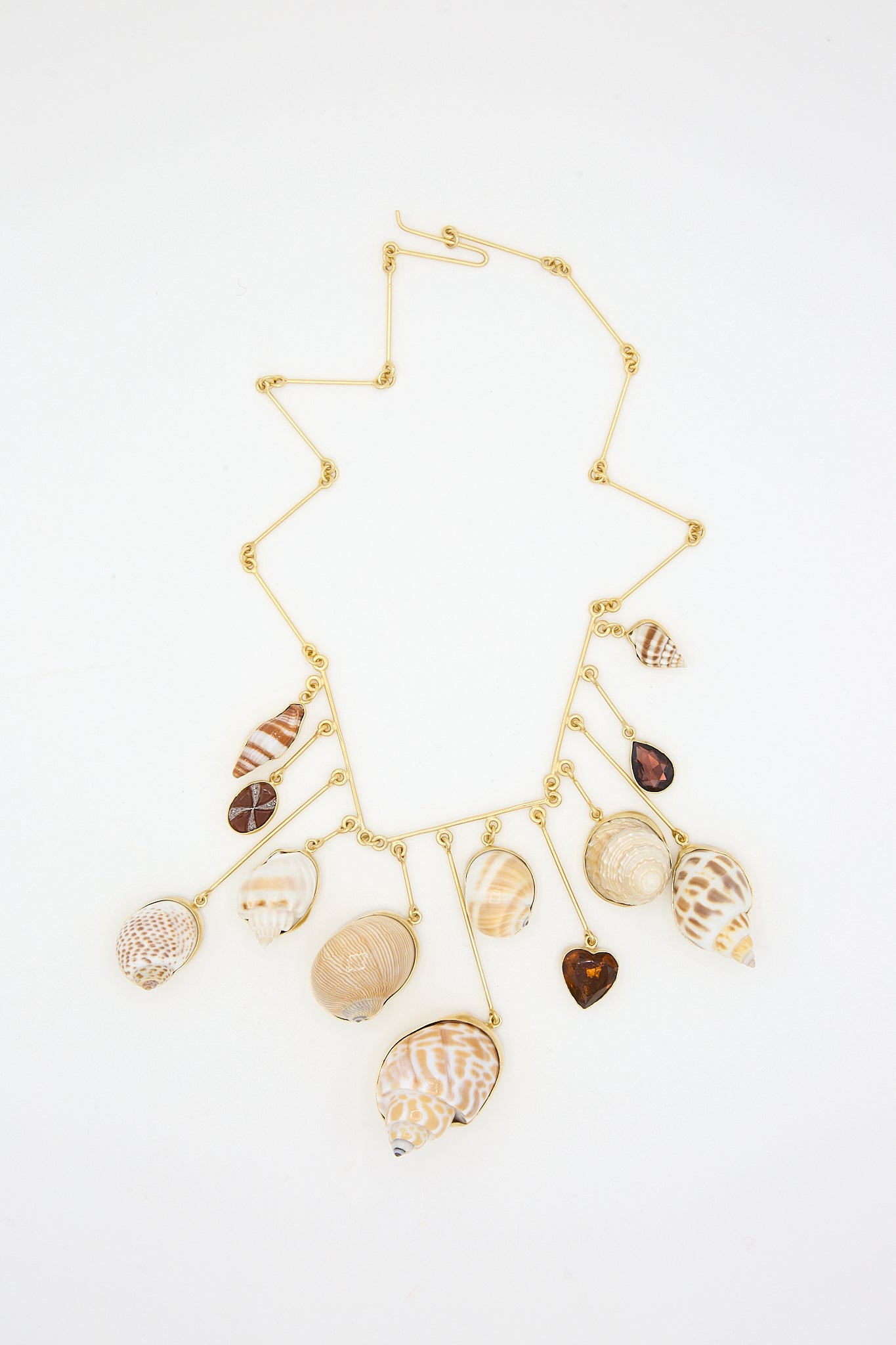 A Wire Charm Drop Necklace with shells, Carnelian beads, and 18k gold-plated silver on it by Grainne Morton.