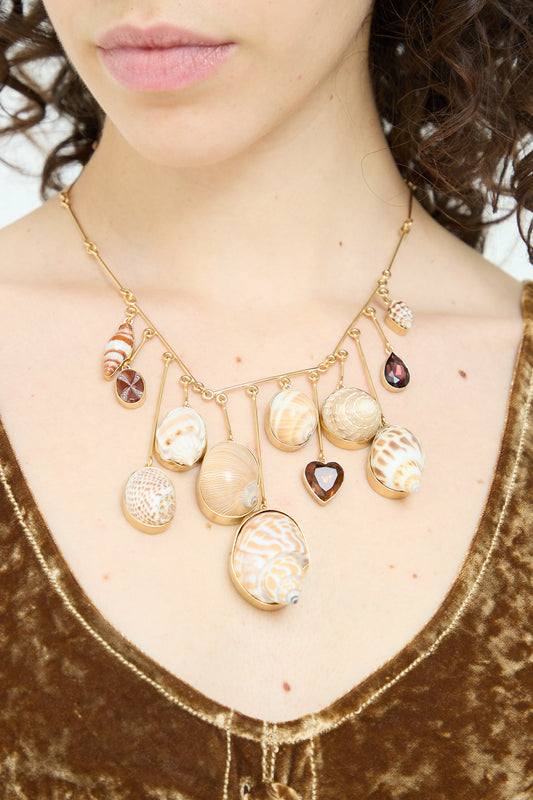 A woman wearing a Grainne Morton Wire Charm Drop Necklace with shells on it.