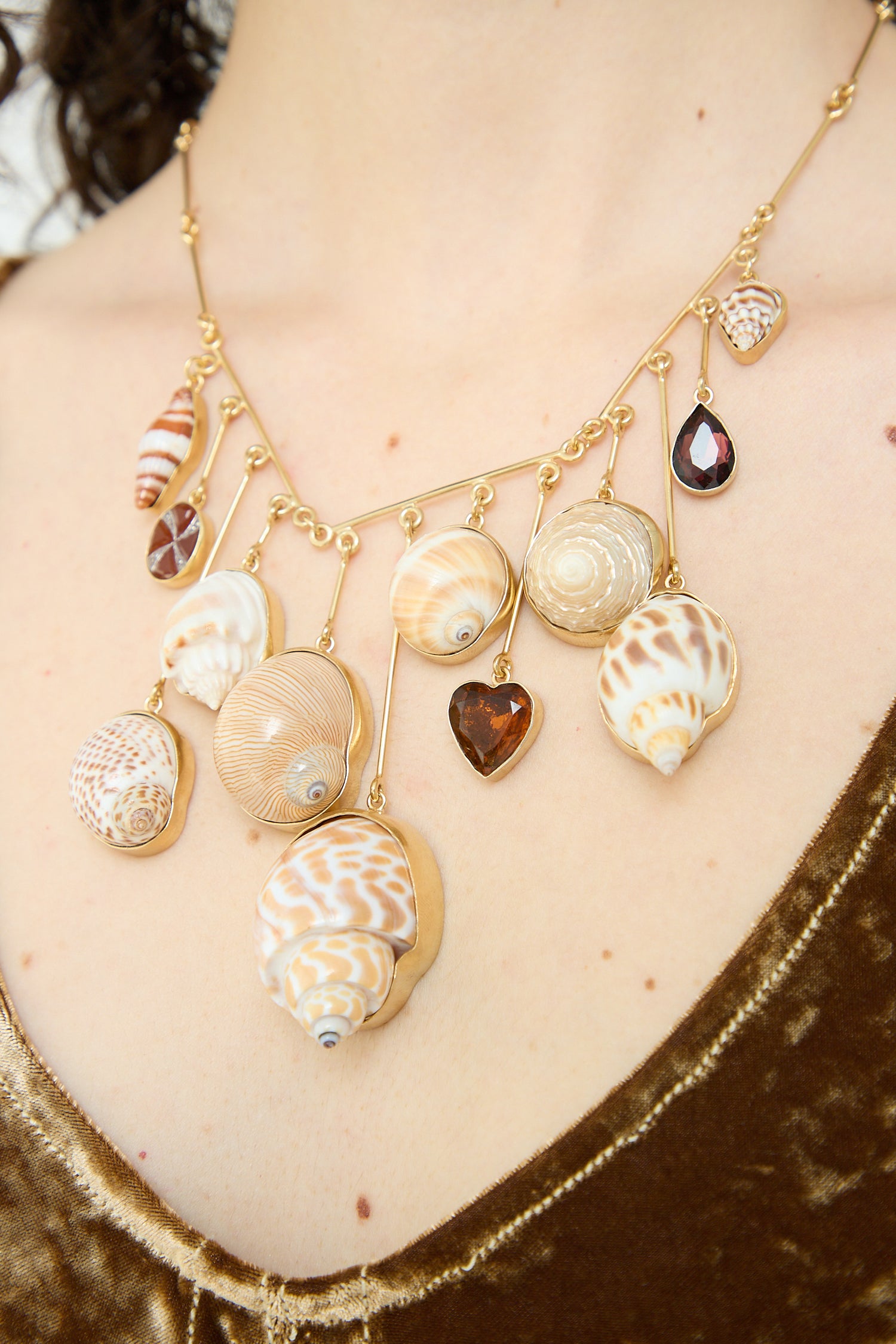 A woman is wearing a Grainne Morton Wire Charm Drop Necklace with shells on it.