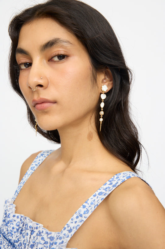 Woman with long dark hair wears a blue floral dress and Grainne Morton Five Charm with Victorian Drop Earrings, looking at the camera against a plain background.