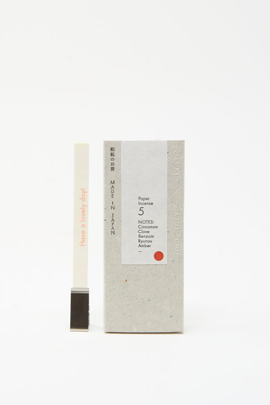 A box of Morihata Washi Paper Incense Strips in Smoky Comfort stands beside a natural aroma strip reading "Have a lovely day!"—held upright by a metal holder; crafted and made in Japan.