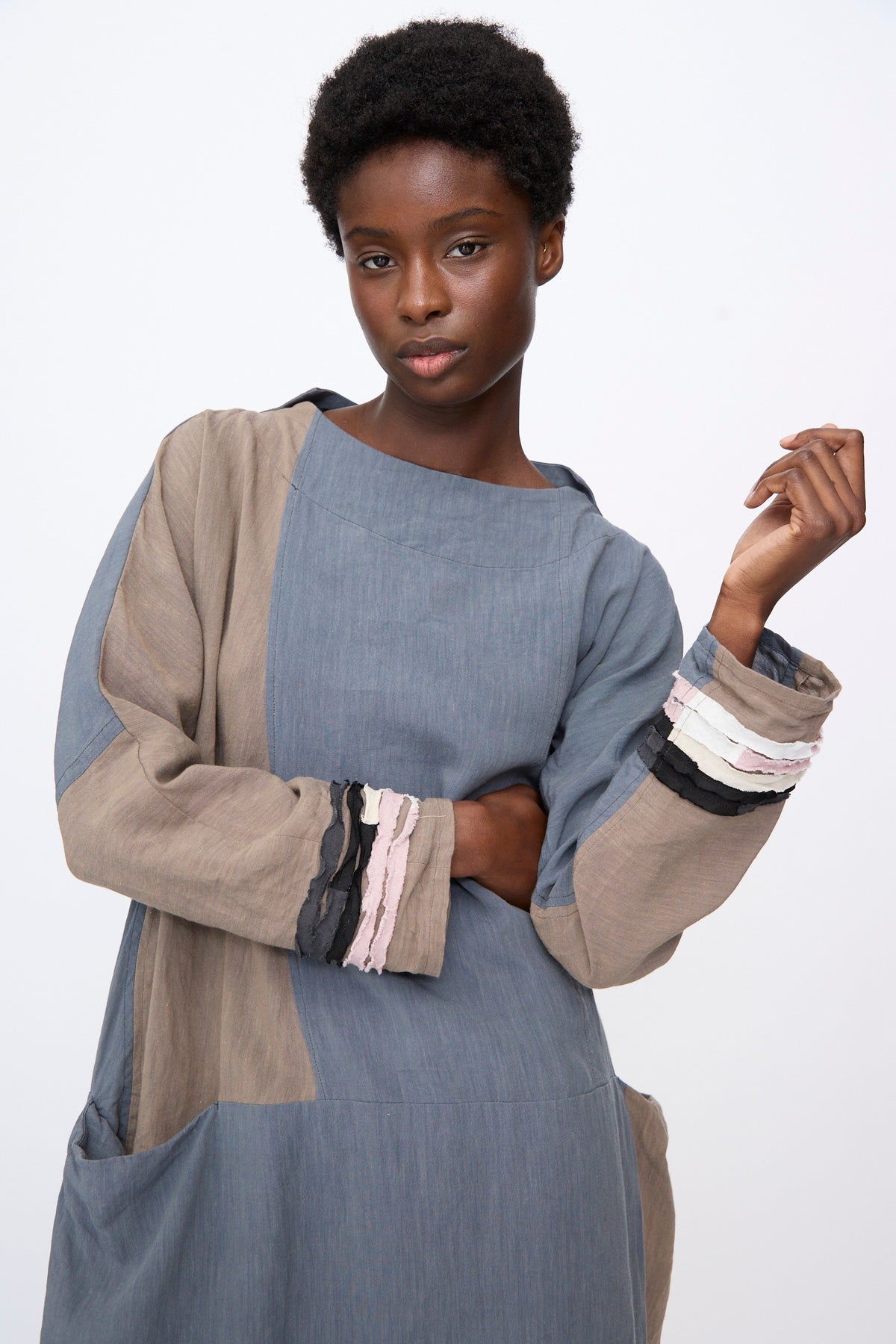 Hallelujah Berger des Montagne de la Castille Dress in Blue Mix, a knee-length, linen blend robe with blue and tan color-blocked panels and frayed, layered cuffs in black, white, and pink.