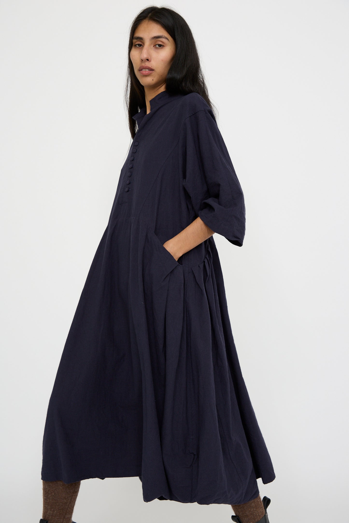 A person stands against a light background wearing the Canvas Acolyte Robe in Navy by Hallelujah, which features a relaxed fit and elbow-length bell sleeves.