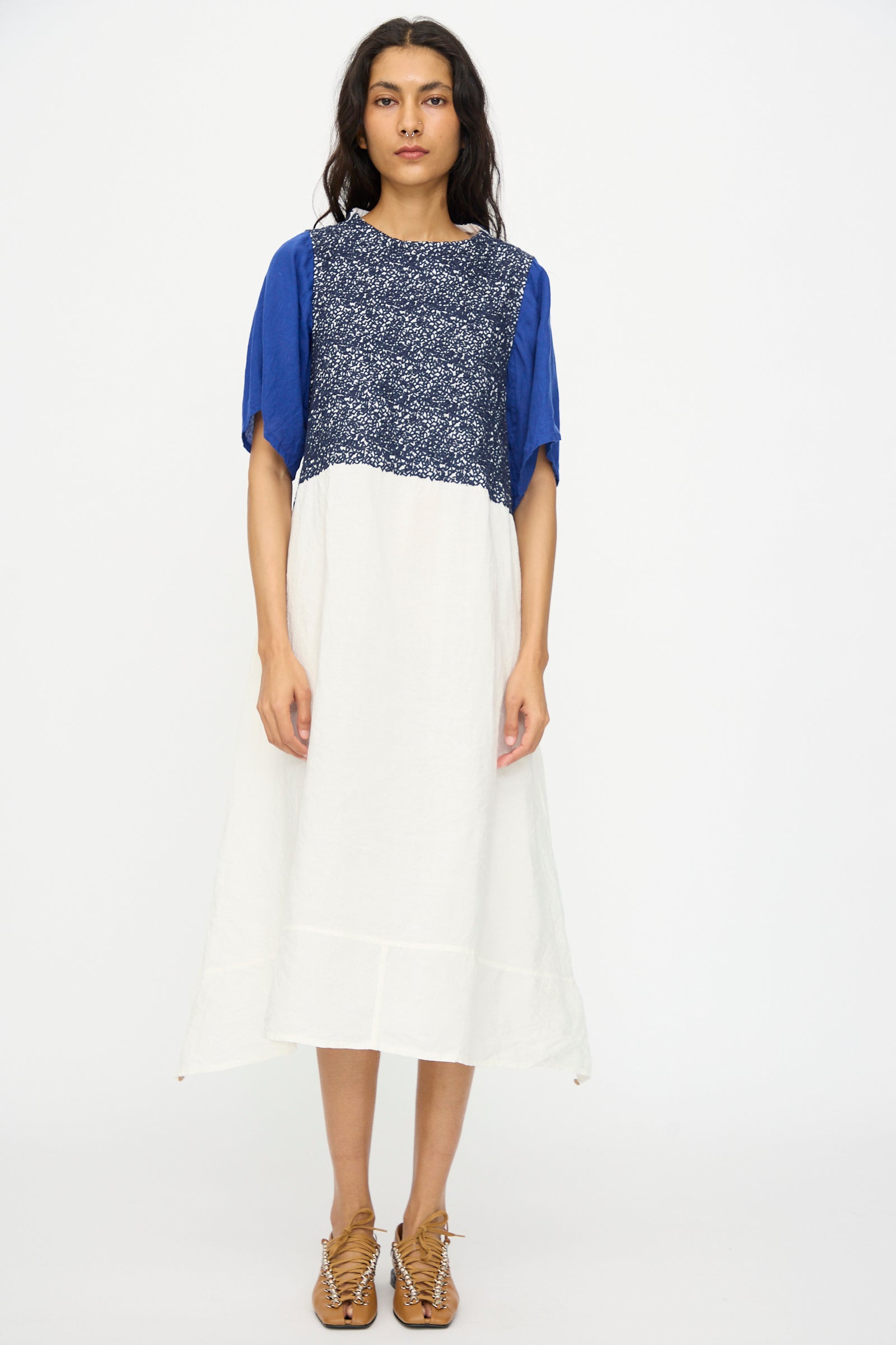A person wears the Hallelujah French Linen La Pucelle Dress in Off White Navy Stitch, short-sleeved and made in Japan, paired with tan lace-up shoes against a plain background.