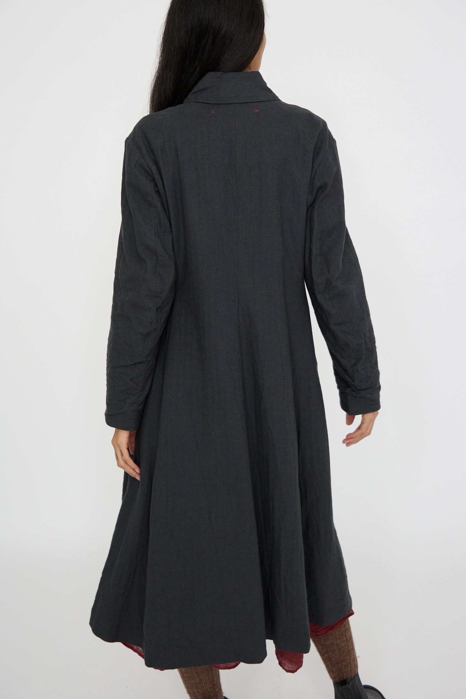 A rear view of a person modeling the Hallelujah Herringbone Early 20th c. Manteau in Gray, which features a classic fold-over collar, against a plain white background.