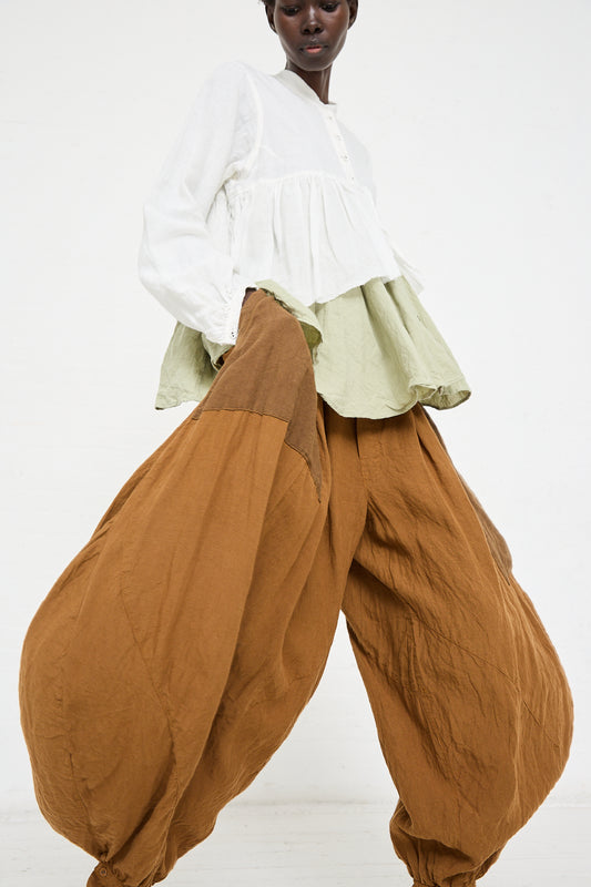 A person models a white, flowy top with layered green fabric and loose, handmade in Kyoto brown Linen Bloomer in Coffee by Hallelujah, all set against a plain white background.