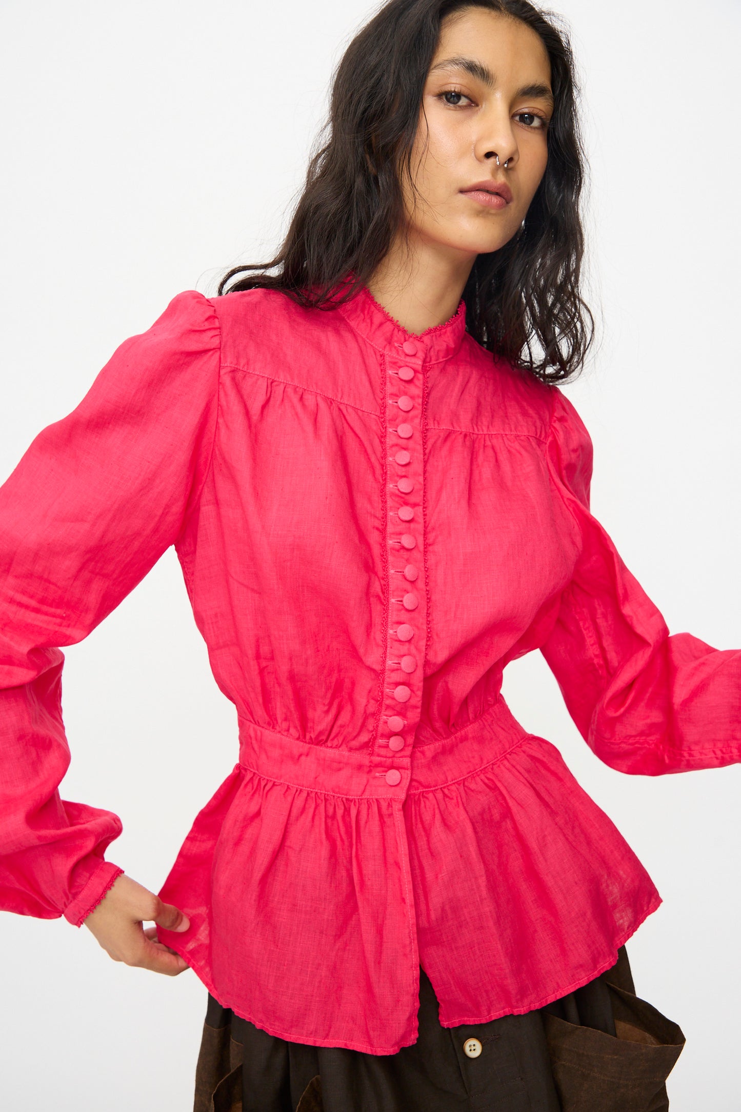 A person wears the Hallelujah Linen Réplique de Chemise Victorienne in Cherry Red—an elegant, long-sleeve blouse inspired by Japanese styles—paired with brown pants, posing against a plain white background.