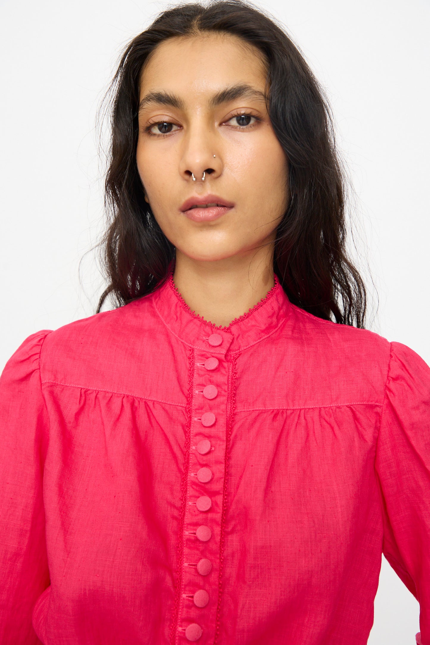 A person with long dark hair wears the Hallelujah Linen Réplique de Chemise Victorienne in Cherry Red, featuring long sleeves and puffed shoulders, standing against a plain white background.