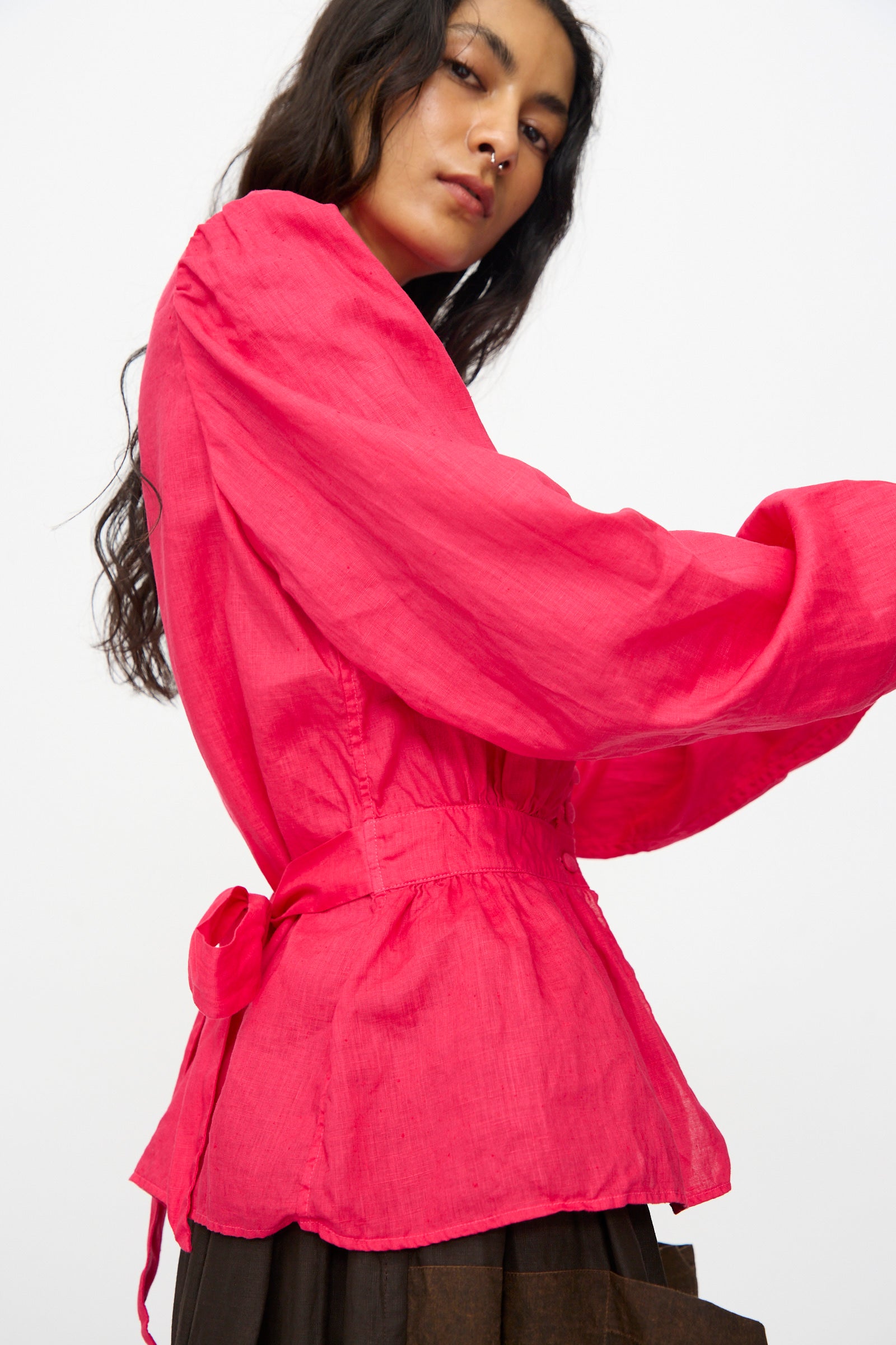 A person with long dark hair wears the Hallelujah Linen Réplique de Chemise Victorienne in Cherry Red, a long-sleeve blouse with a tie at the back, standing against a plain white background. Inspired by classic Japanese style.