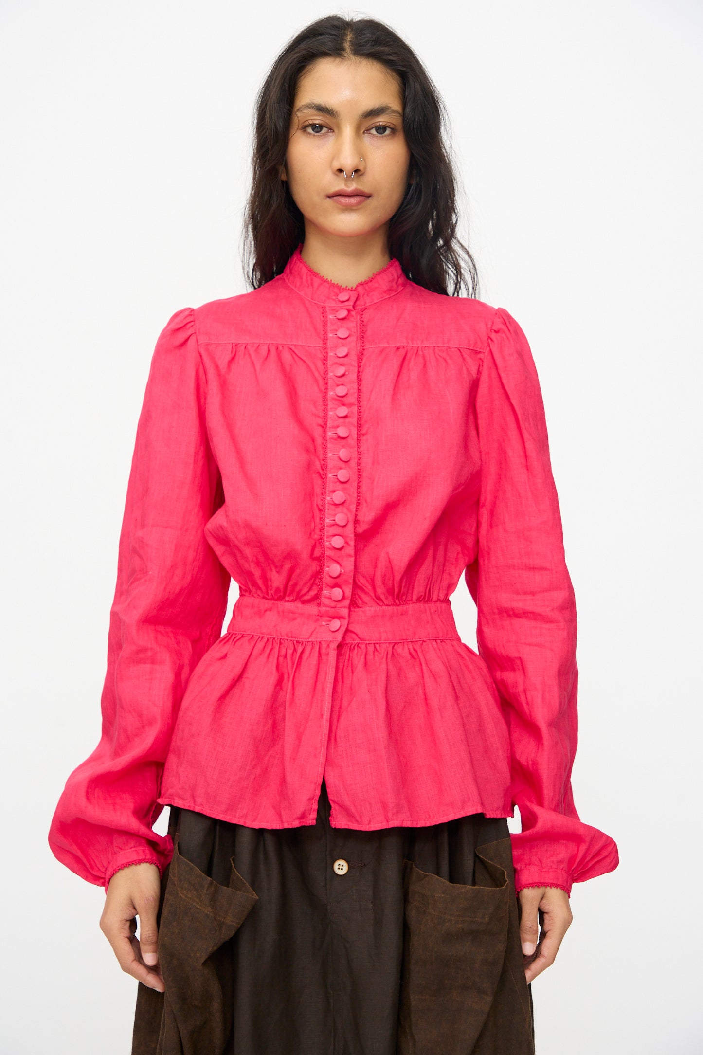 A woman stands facing forward wearing the Hallelujah Linen Réplique de Chemise Victorienne in Cherry Red, paired with a dark brown skirt, made in Japan, against a plain white background.