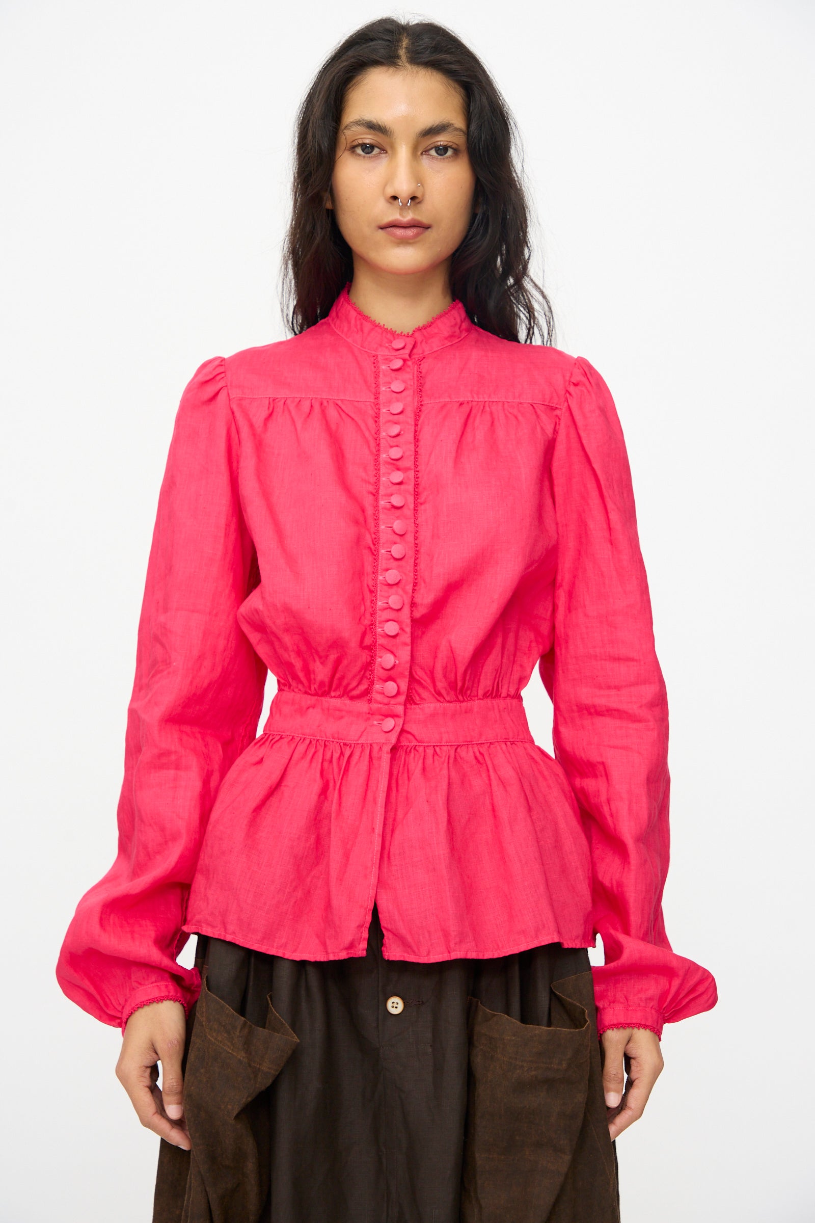 A woman stands facing forward wearing the Hallelujah Linen Réplique de Chemise Victorienne in Cherry Red, paired with a dark brown skirt, made in Japan, against a plain white background.