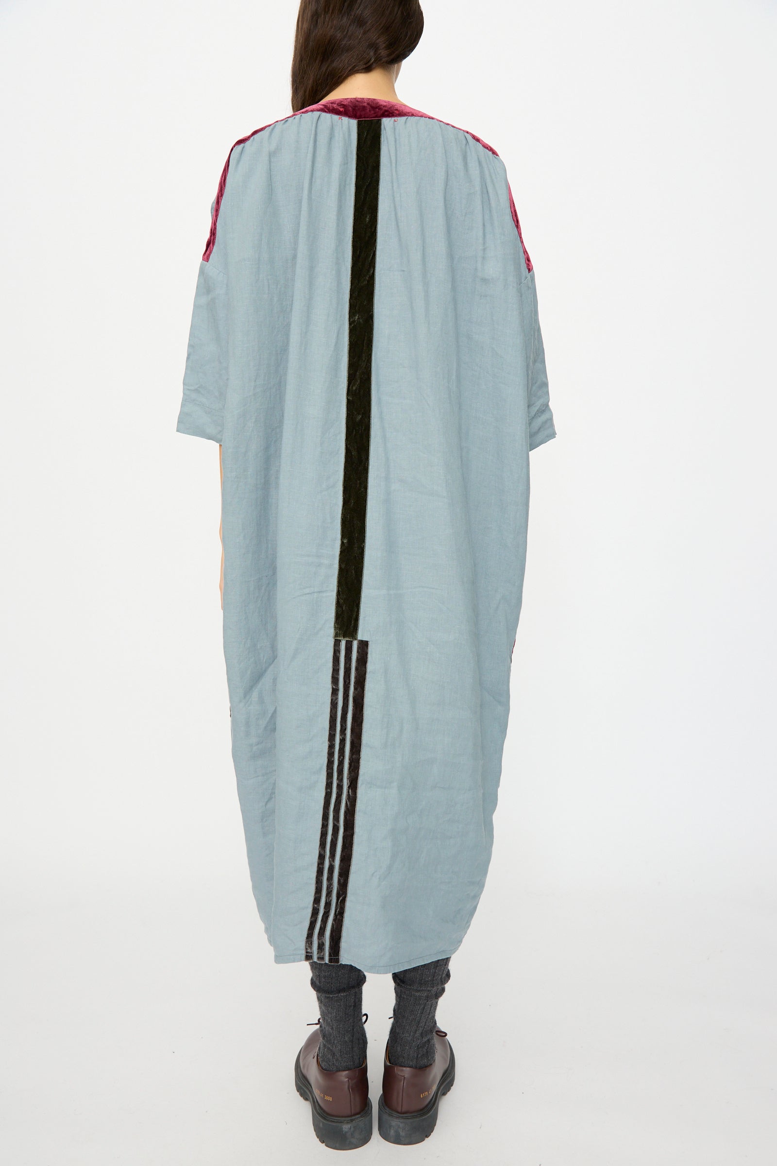 Person stands with back to camera, wearing Hallelujah's Linen Robes de couture 1930s in Blue—relaxed fit with dark vertical stripes—paired with grey pants and brown platform shoes. This effortlessly chic look is made in Japan.
