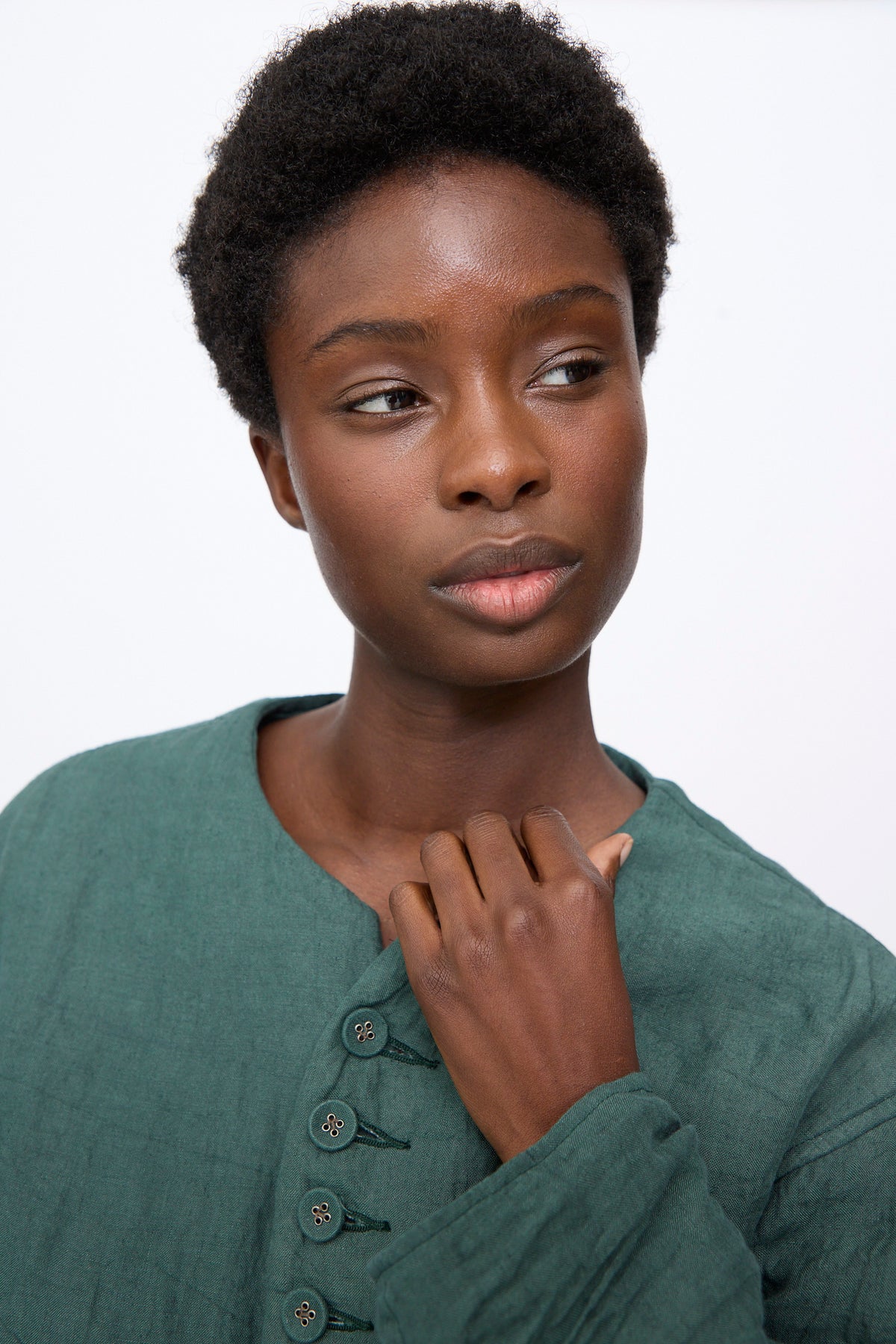 A person wearing a dark green Hallelujah Linen Veste de Berger linen jacket with a button-up placket.