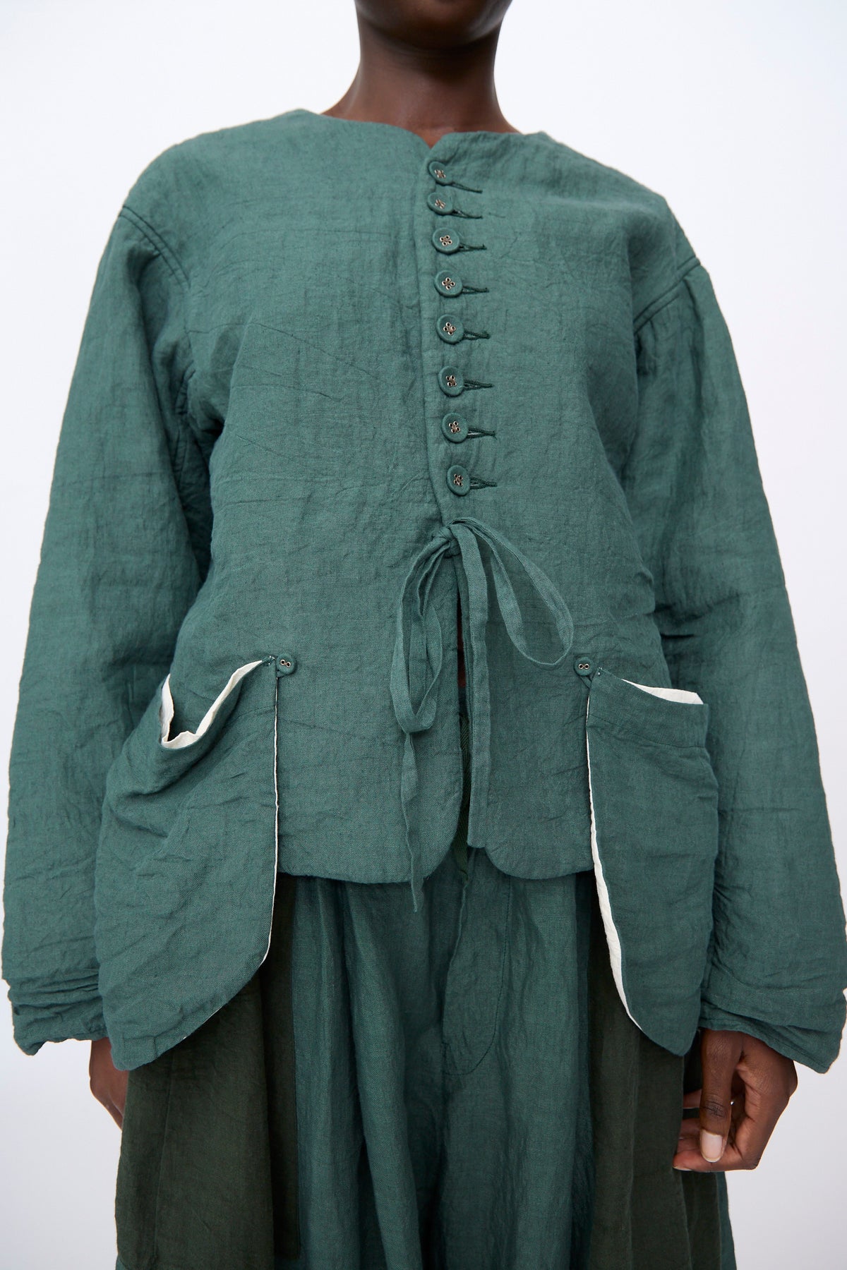 Green Hallelujah Linen Veste de Berger with a front tie closure and two large exterior pockets, made in Japan.