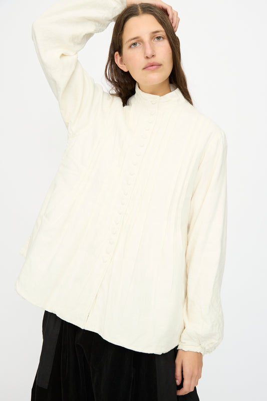 A person with long brown hair wears the Hallelujah Silk and Linen Chemise de Baptême in White and a black skirt, standing against a plain white background.