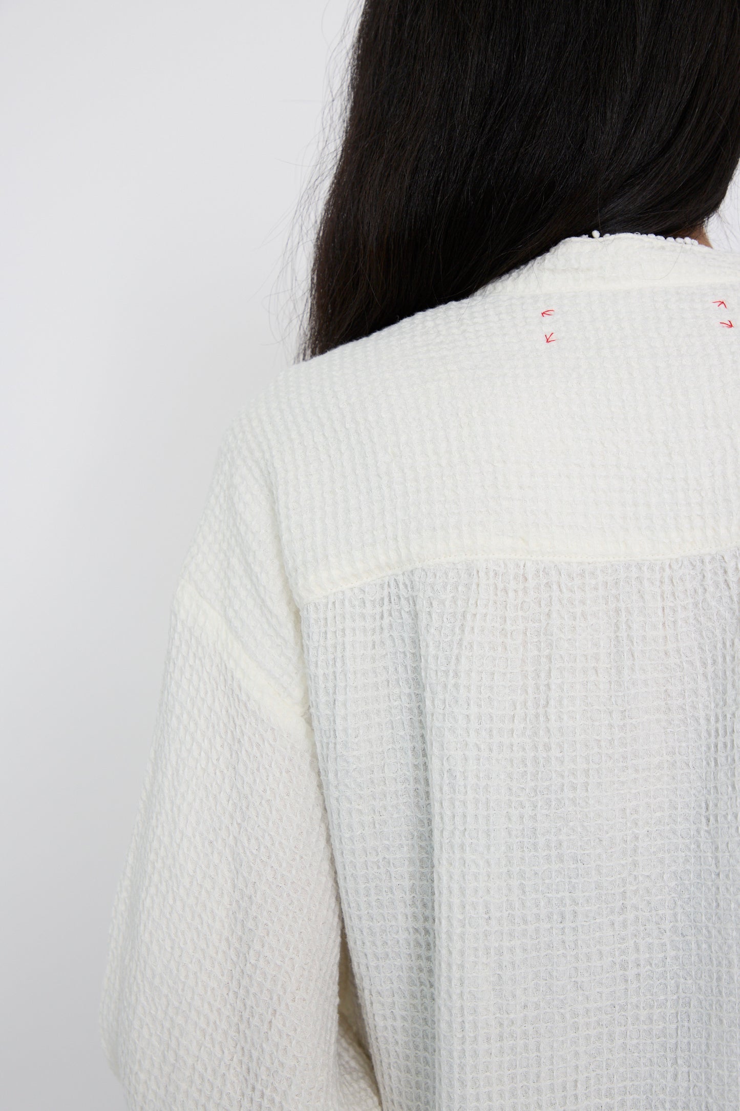 A person with long hair, wearing the Hallelujah Waffle Linen Robe Chemise in Milky White, is photographed from behind.