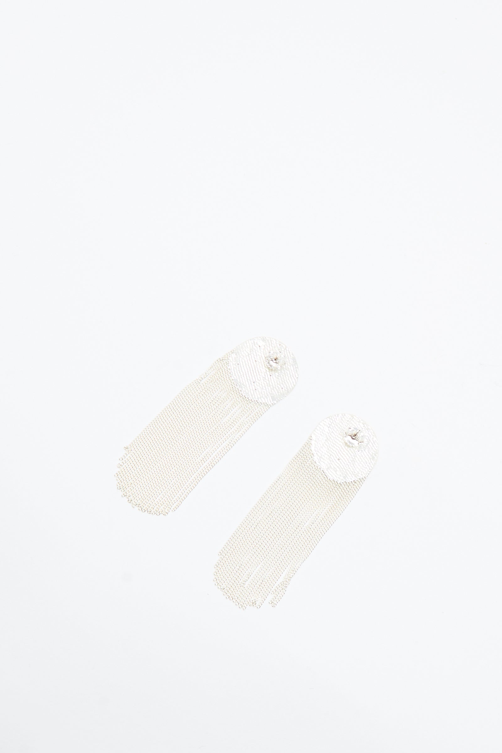 The Dot Earrings in Silver by Hannah Keefe are long, handmade silver earrings with circular tops and cascading chain fringes, shown on a white background.