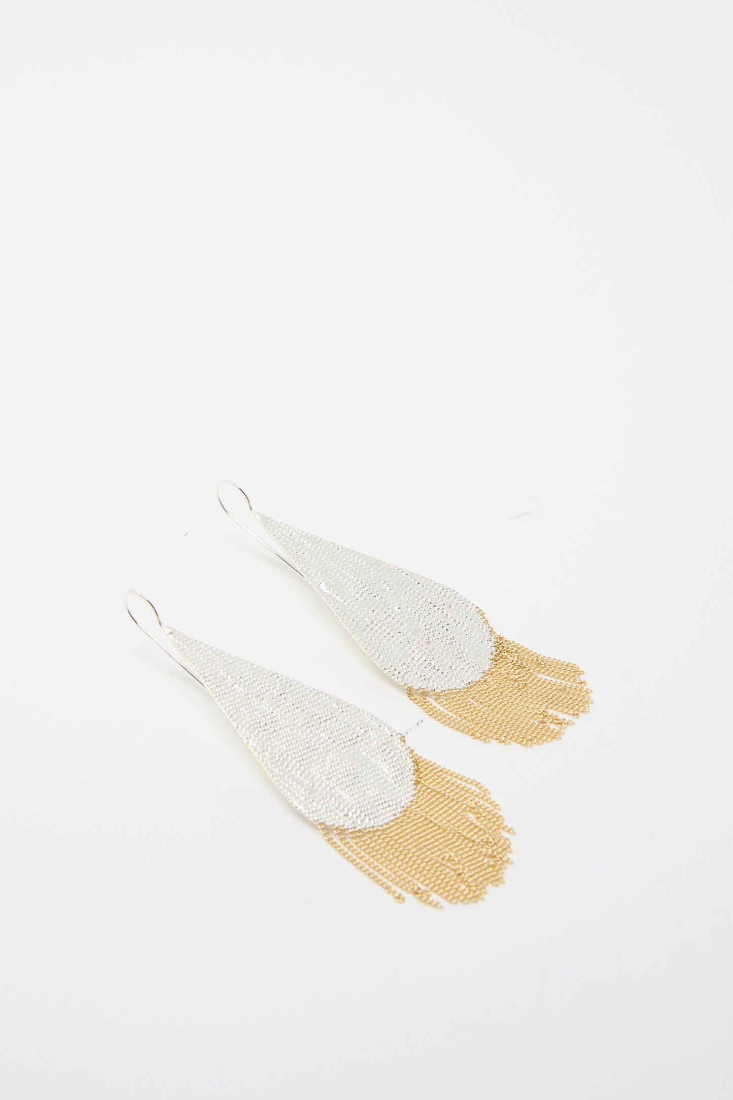 The Drip Earrings by Hannah Keefe showcase teardrop shapes made with silver solder, complemented by gold chain fringe on a white background.