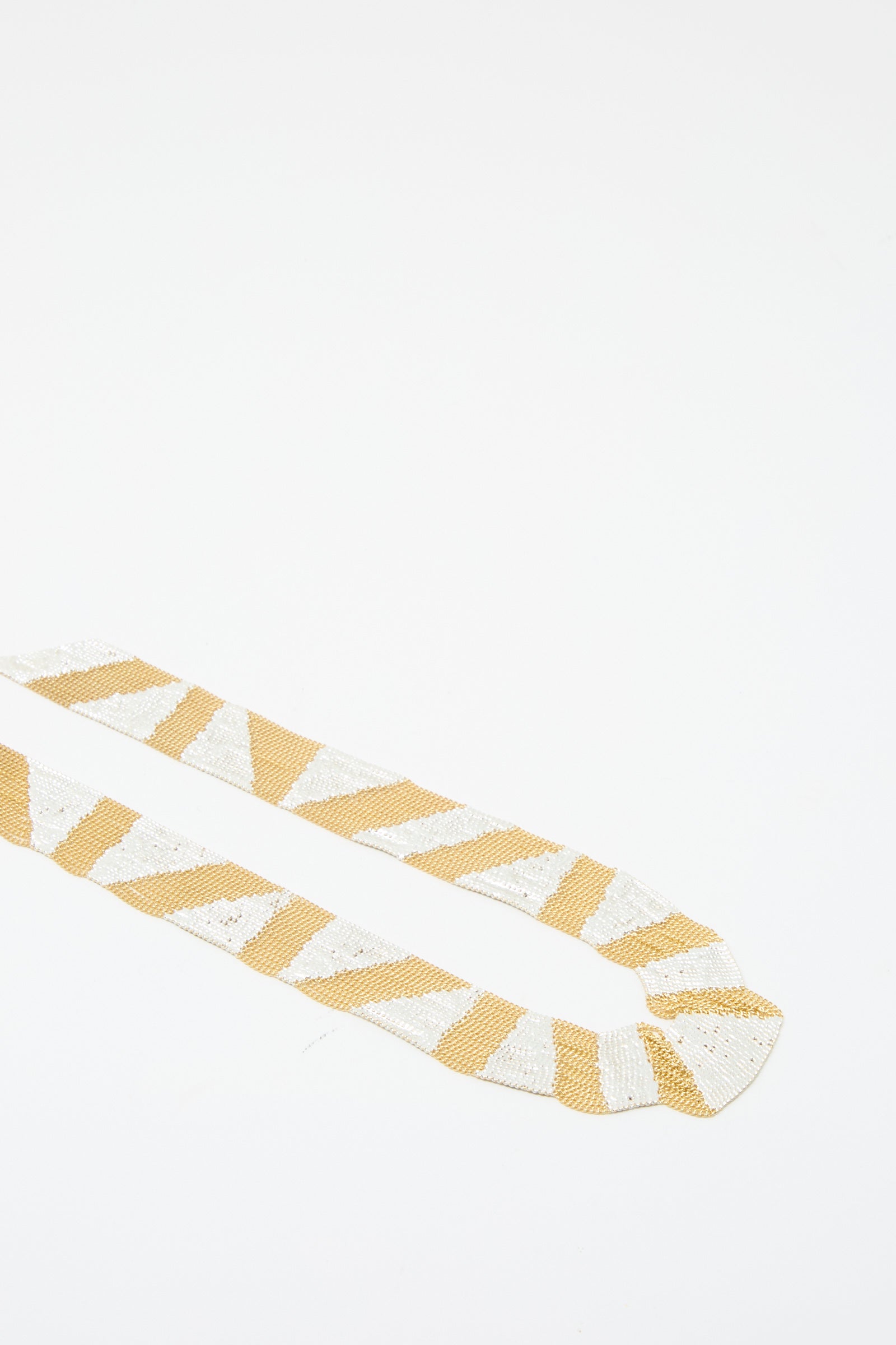 Introducing the Sunny Necklace in Brass and Silver by Hannah Keefe, a handcrafted piece featuring a geometric pattern of alternating brass and silver triangular shapes on a simple background. 