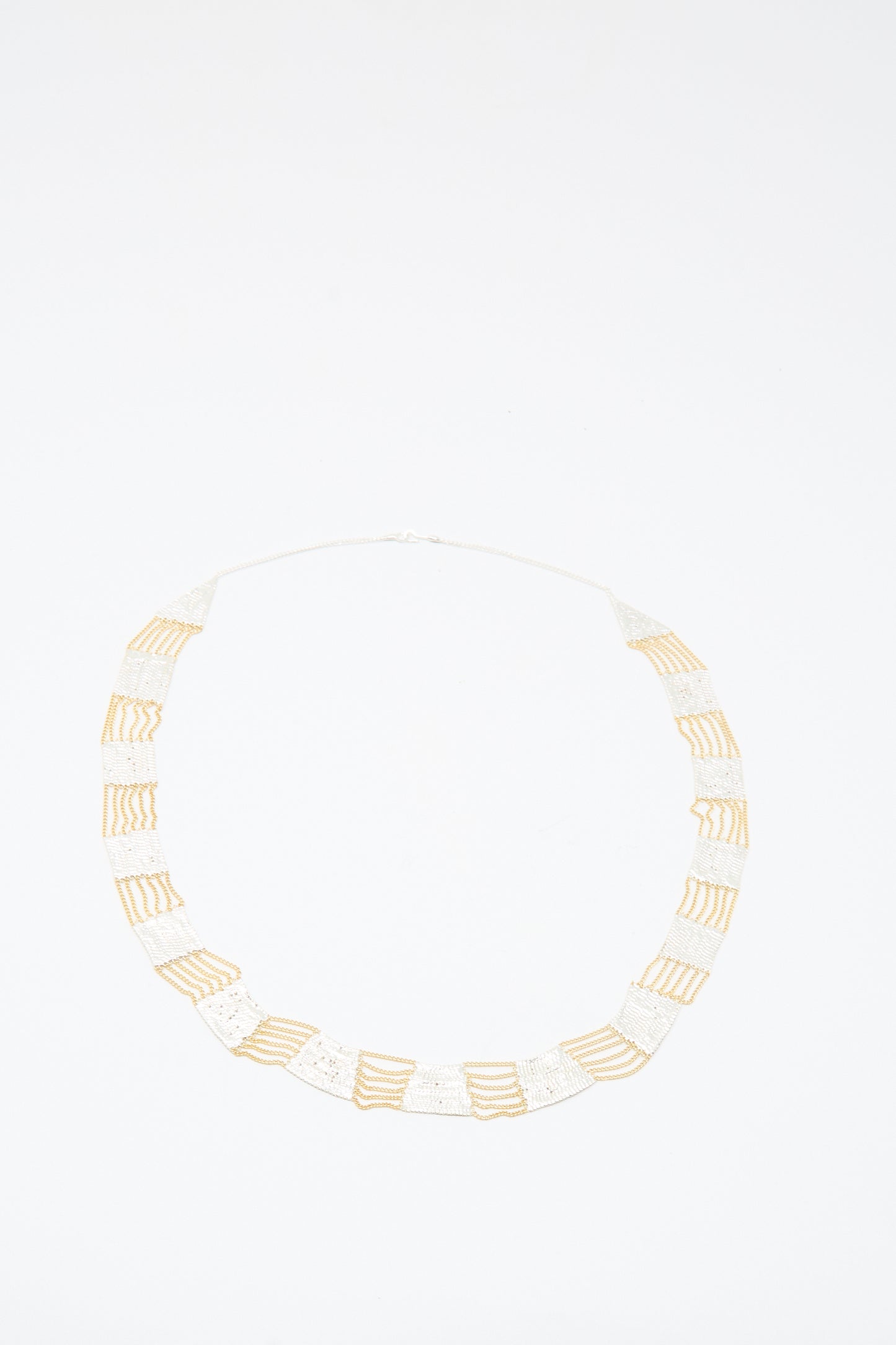 The Hannah Keefe Train Necklace in Brass and Silver features handmade alternating rectangular sections, laid flat on a white background.