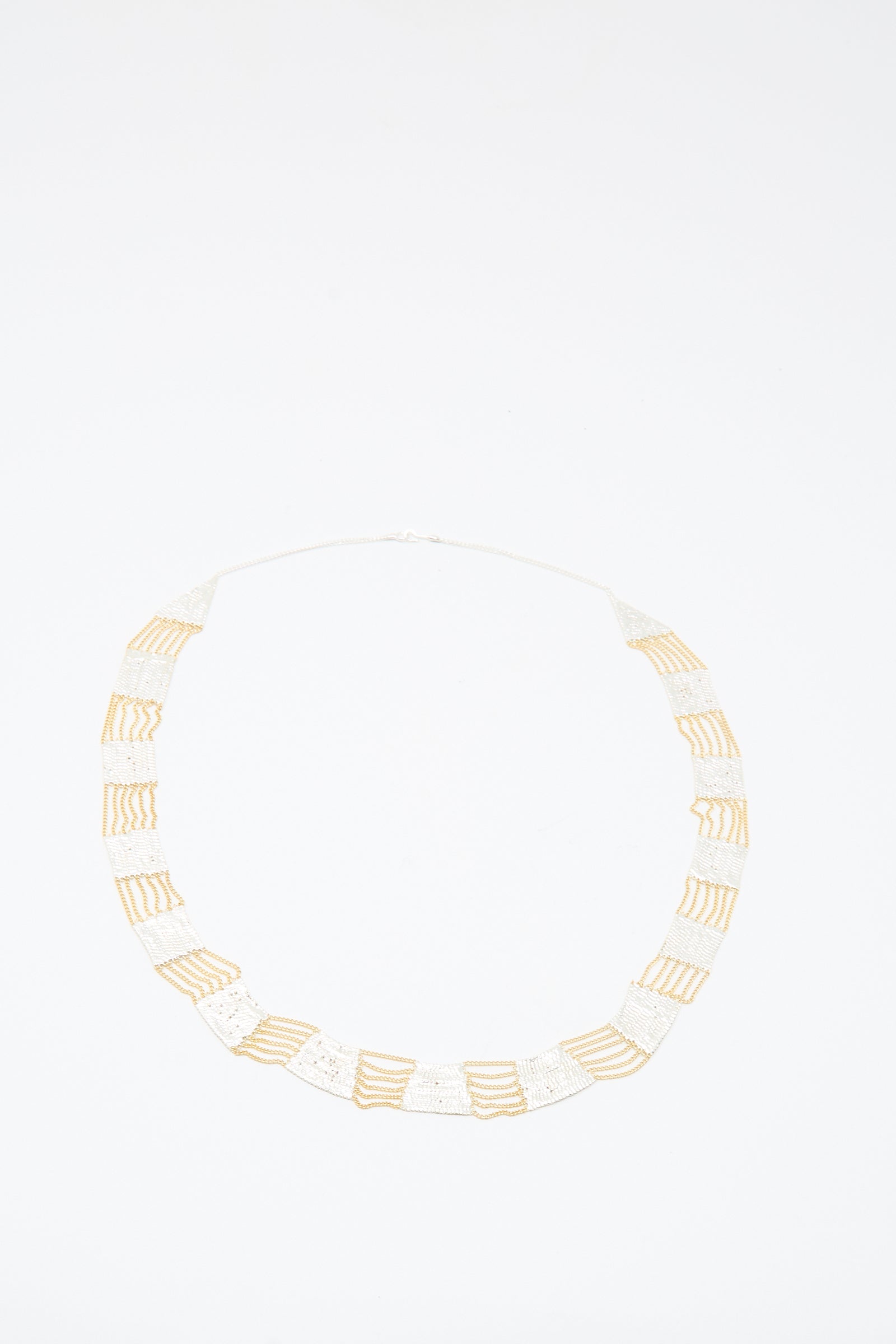 The Hannah Keefe Train Necklace in Brass and Silver features handmade alternating rectangular sections, laid flat on a white background.