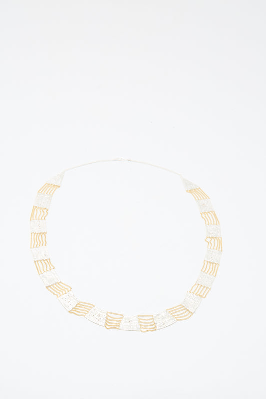 The Hannah Keefe Train Necklace in Brass and Silver features handmade alternating rectangular sections, laid flat on a white background.