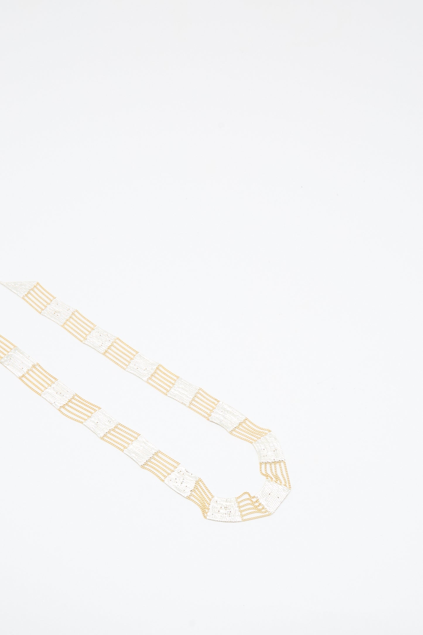 The Train Necklace in Brass and Silver by Hannah Keefe is displayed on a plain white background, showcasing the unique artistry of Los Angeles jewelry.