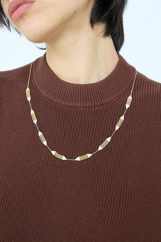 Woman wearing a brown sweater and a handmade, Hannah Keefe Minnow Necklace in Brass Chain and Silver Solder.