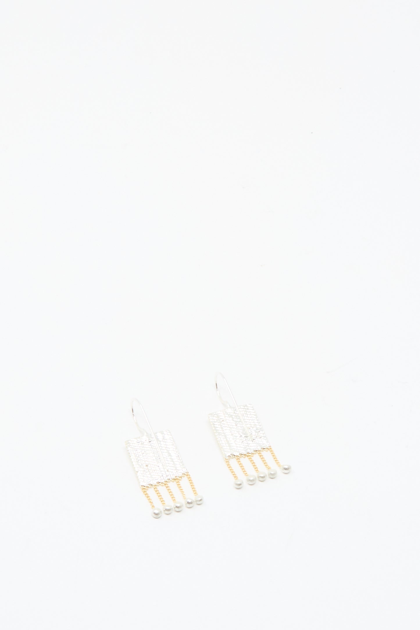 Bauble Earrings in Brass and Silver by Hannah Keefe showcase handmade elegance with white and gold beads on delicate brass chains, set against a plain white background.