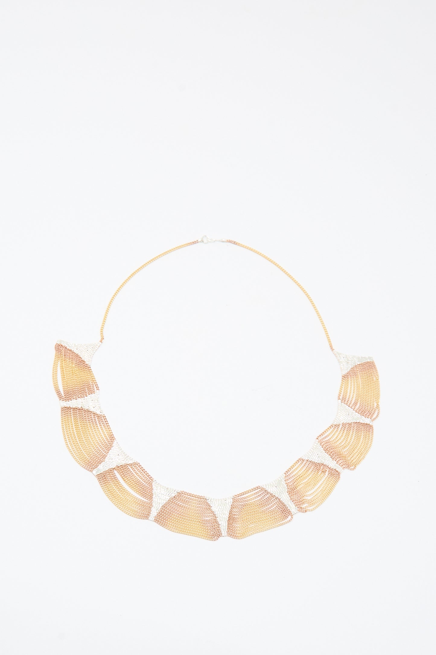The Deanna Necklace in Brass and Silver by Hannah Keefe features large shell-shaped segments on a thin chain, handmade in California, and is shown on a white background.