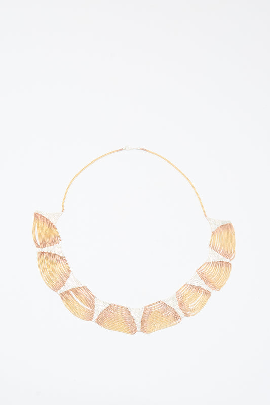The Deanna Necklace in Brass and Silver by Hannah Keefe features large shell-shaped segments on a thin chain, handmade in California, and is shown on a white background.
