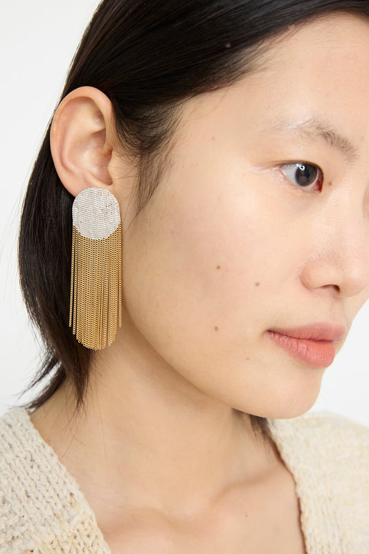 Close-up of a person wearing Hannah Keefe's Dot Earrings in Brass and Silver,  highlighting their handmade design with silver circle studs and a brass chain fringe.