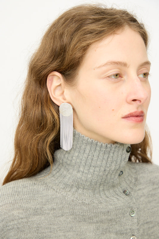 Woman with long brown hair wears a grey ribbed turtleneck sweater and Hannah Keefe's Dot Earrings in Silver, gazing to the side against a plain background.
