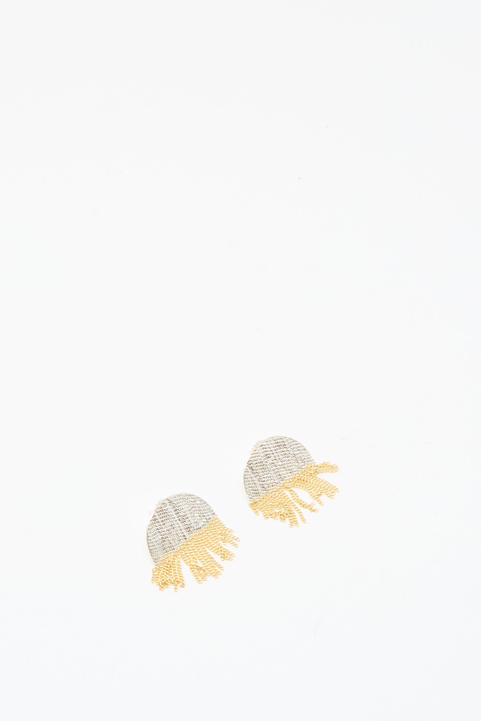 The Half Circle Studs in Brass and Silver by Hannah Keefe, featuring small handmade earrings with light gray tops and yellow brass chain fringe, are displayed on a plain white background.
