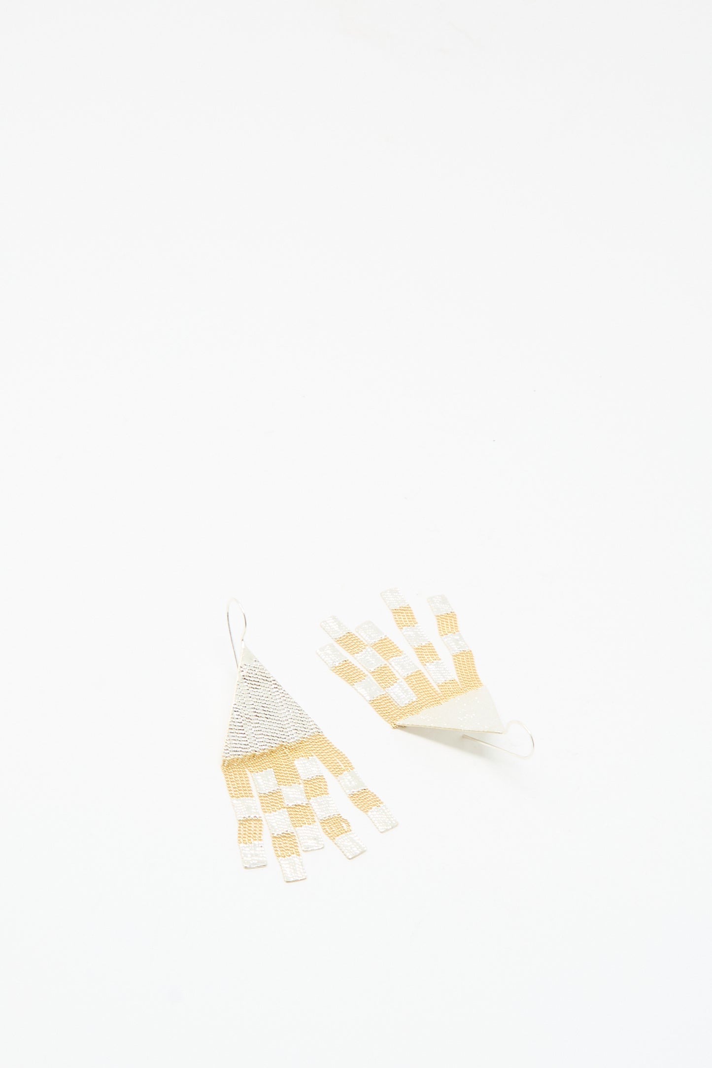 Handmade in California, the Scotch Earrings in Brass and Silver by Hannah Keefe are woven triangle drop earrings featuring cream and gold checkerboard patterns on a white background.