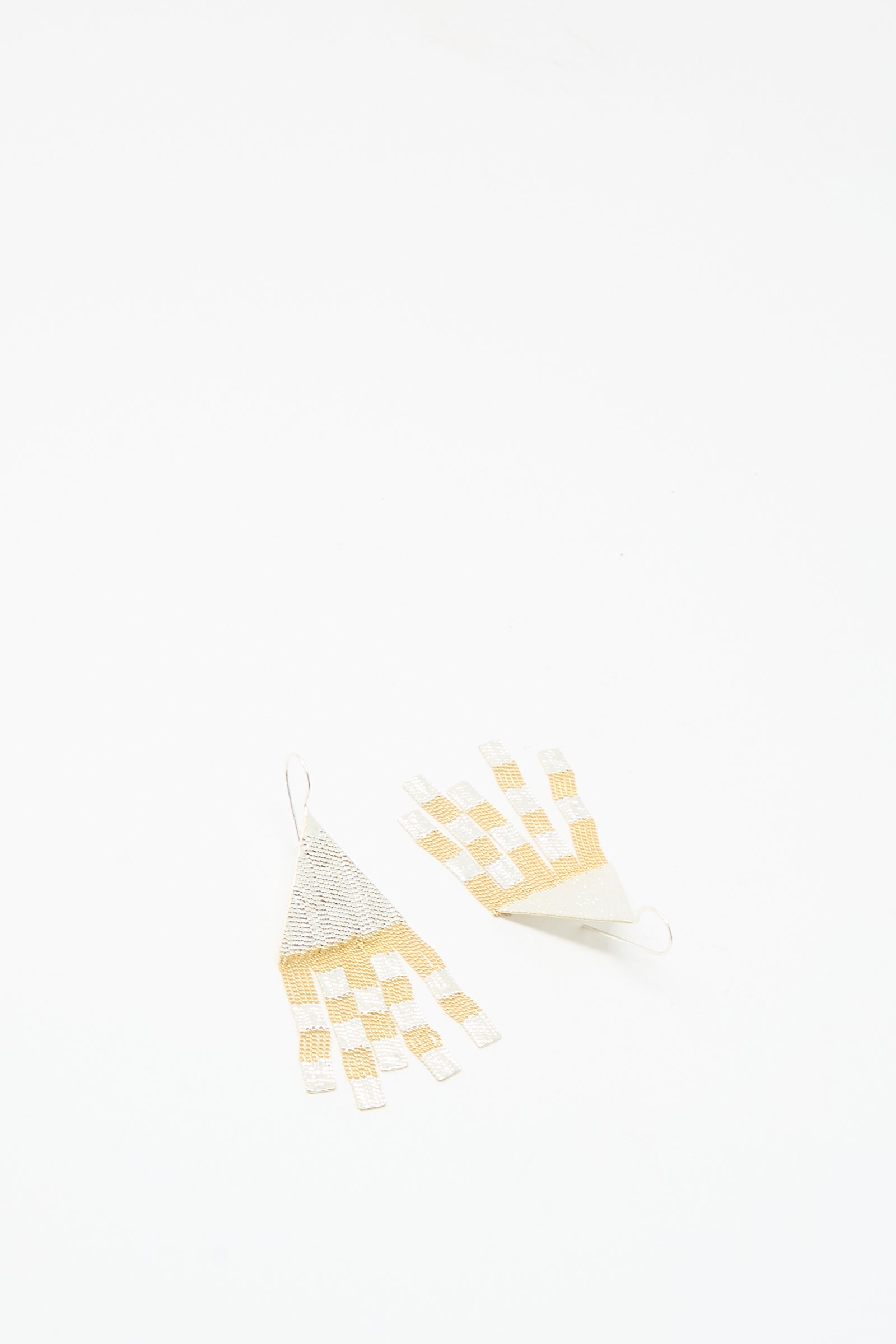 Handmade in California, the Scotch Earrings in Brass and Silver by Hannah Keefe are woven triangle drop earrings featuring cream and gold checkerboard patterns on a white background.