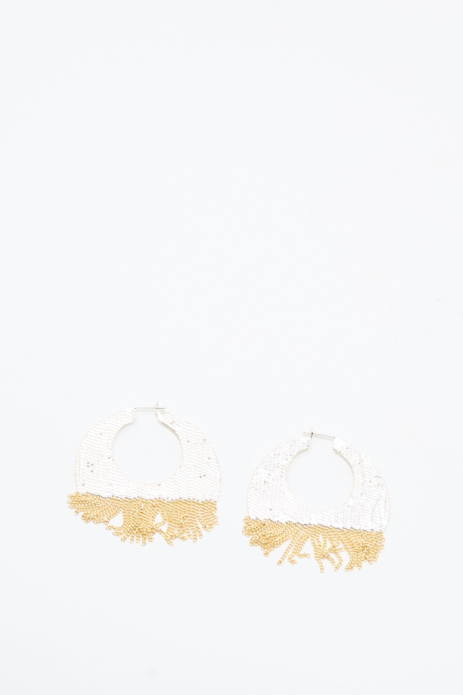 The True Hoops in Brass and Silver by Hannah Keefe are handmade earrings with round white beads on top and gold fringe beading on the bottom, shown against a white background.
