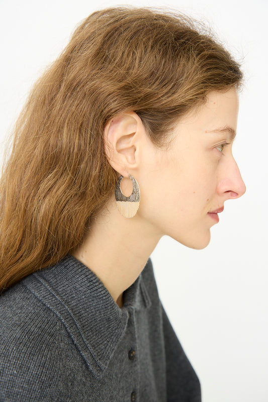 Woman with long brown hair wears the Hannah Keefe True Hoops in Brass and Silver, shown in profile against a plain white background, paired with a gray collared sweater.