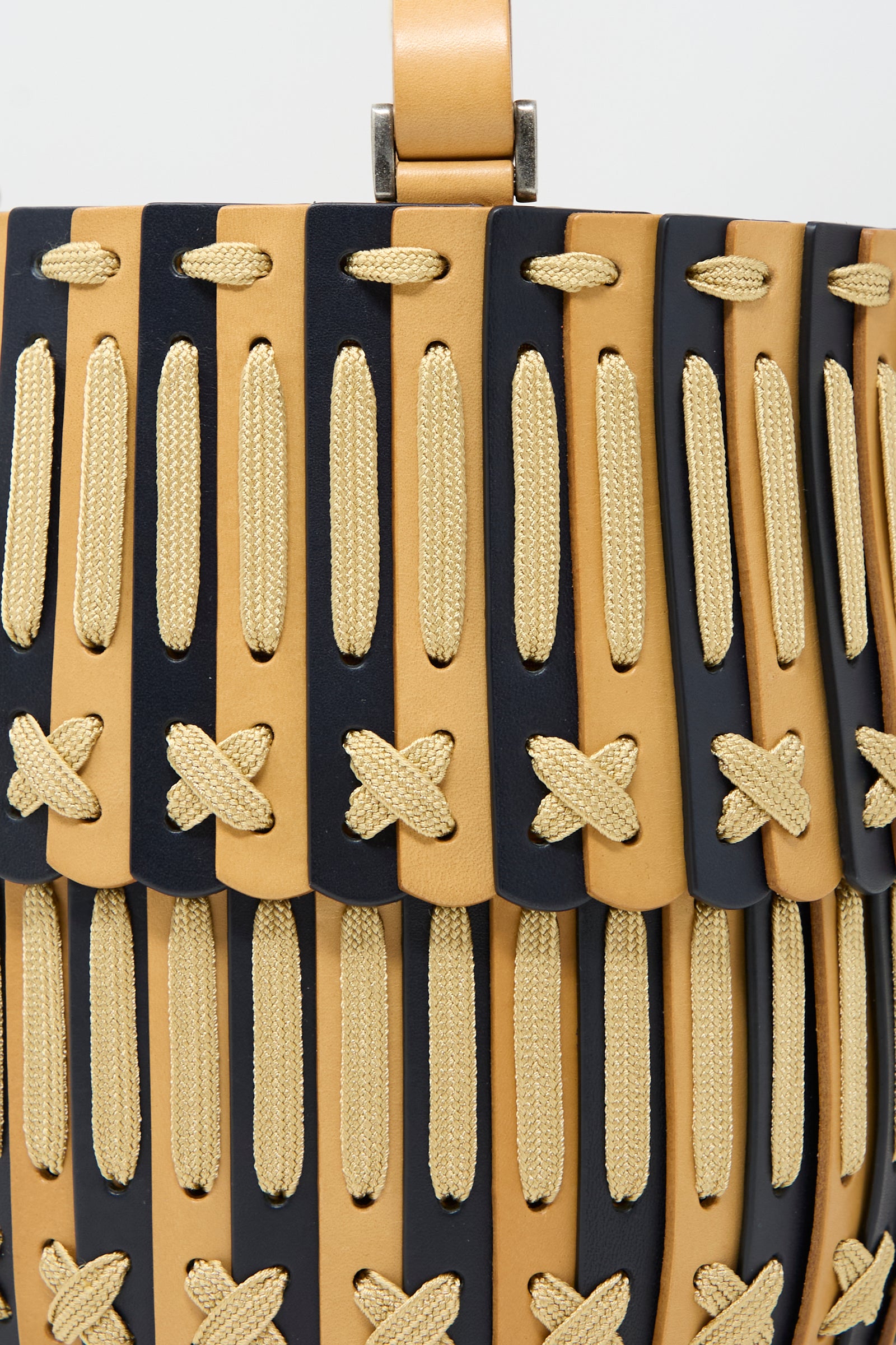 Close-up of Hatori's handcrafted Leather Bucket Bag in Natural and Midnight Blue, featuring beige rope details and X-shaped stitches, made from vegetable-tanned leather with an adjustable strap.