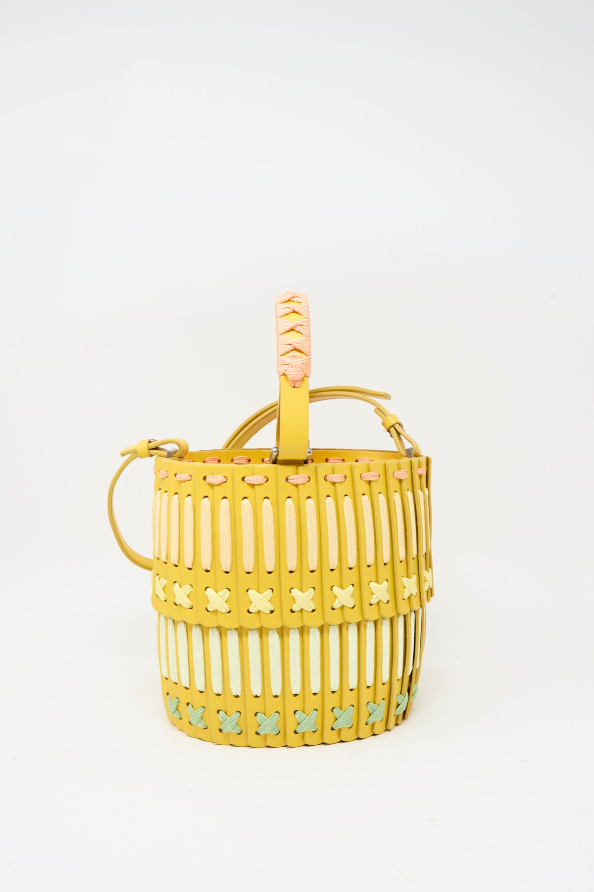 Hatori Leather Bucket 80 Artist Edition with Holly Coulis in Yellow: a handcrafted bucket bag with intricate woven detailing in yellow, laced with pale pink, white, and light green accents.